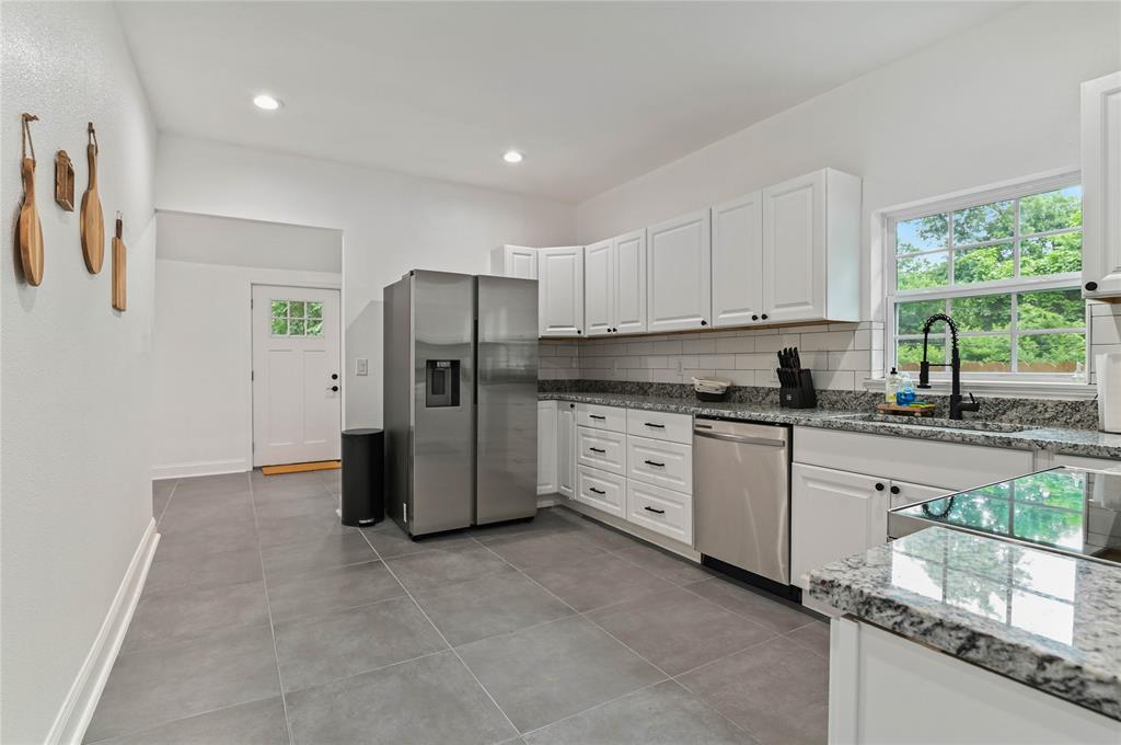 1106 West Chestnut Street Denison, TX 75020 - Photo 26 of 38 Kitchen featuring light tile patterned floors, stainless steel appliances, backsplash, and white cabinets