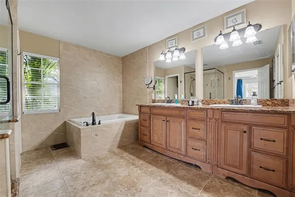 a spacious bathroom with a granite countertop sink a large mirror and a bathtub