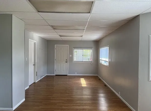 a view of an empty room with wooden floor and a window