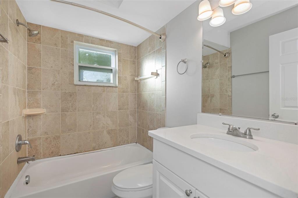 224 Whisper Lake Road Palm Harbor, FL 34683 - Photo 17 of 23 a bathroom with a granite countertop sink a toilet a mirror a bathtub and shower