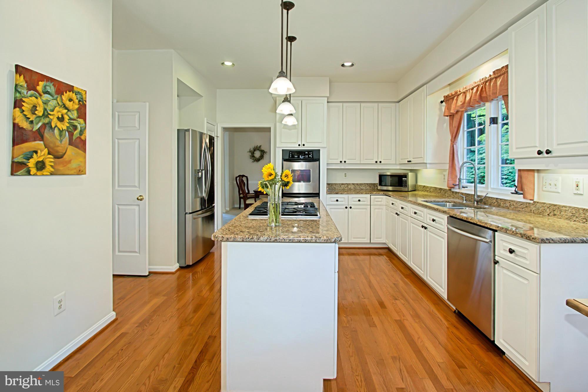 8127 Ridge Creek Way Springfield, VA 22153 - Photo 12 of 30 a large kitchen with kitchen island a stove a sink a center island and wooden floor