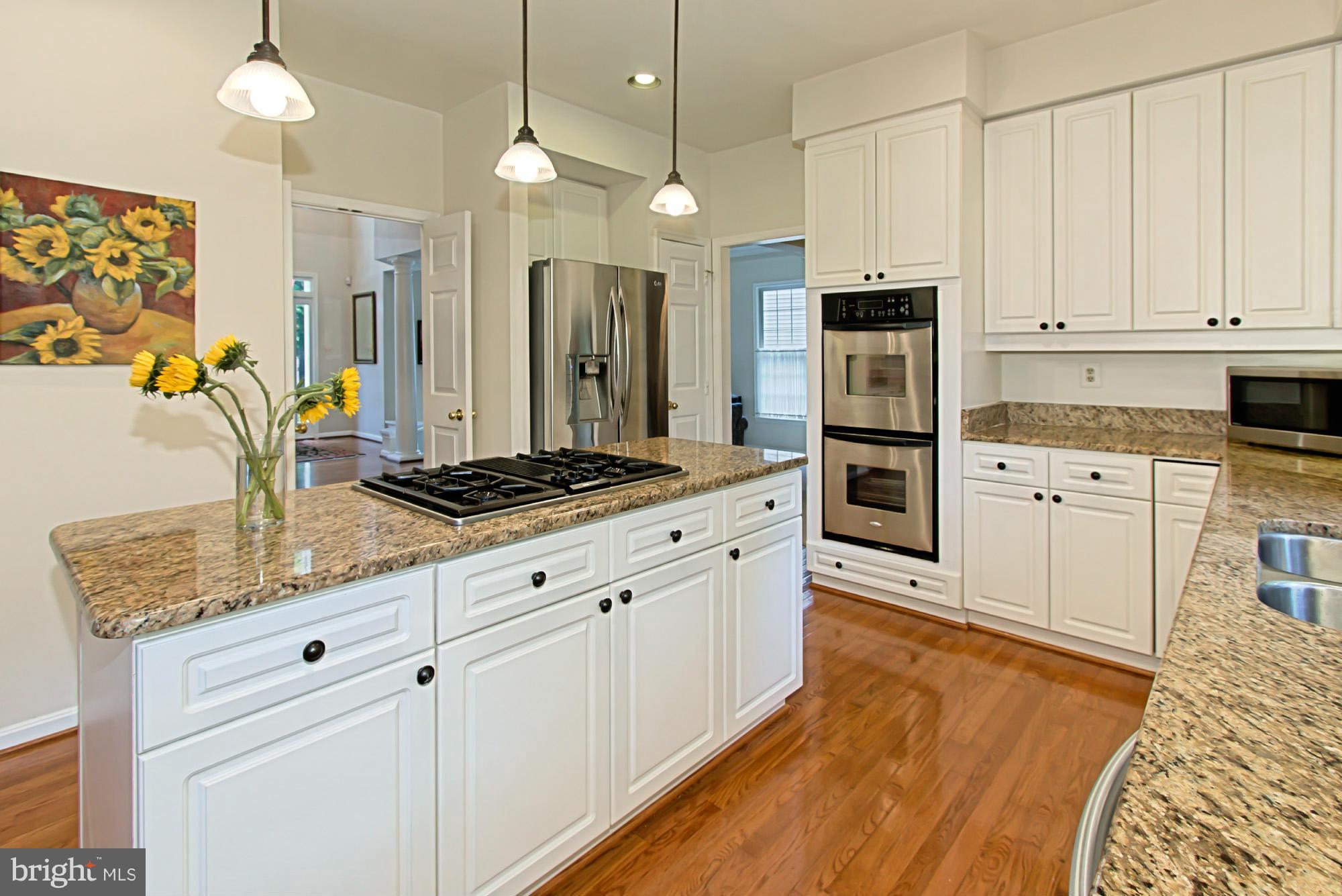8127 Ridge Creek Way Springfield, VA 22153 - Photo 13 of 30 a kitchen with stainless steel appliances granite countertop a stove a sink and white cabinets with wooden floor