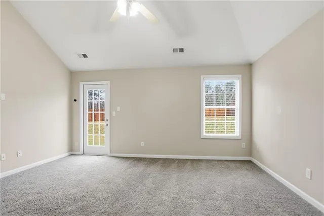a view of an empty room and chandelier fan