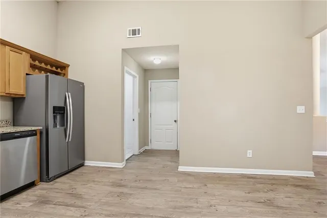 a view of an empty room with kitchen and a window