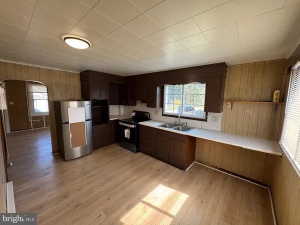 a kitchen with stainless steel appliances kitchen island granite countertop a refrigerator a sink dishwasher a stove and a wooden cabinets with wooden floor