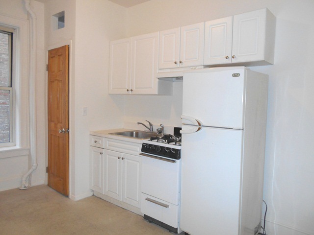 170-172 Spring Street, Unit 7 Manhattan, NY 10012 - Photo 1 of 8 a kitchen with white cabinets and white appliances