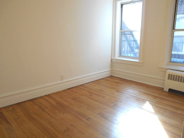 170-172 Spring Street, Unit 7 Manhattan, NY 10012 - Photo 3 of 8 an empty room with wooden floor and windows