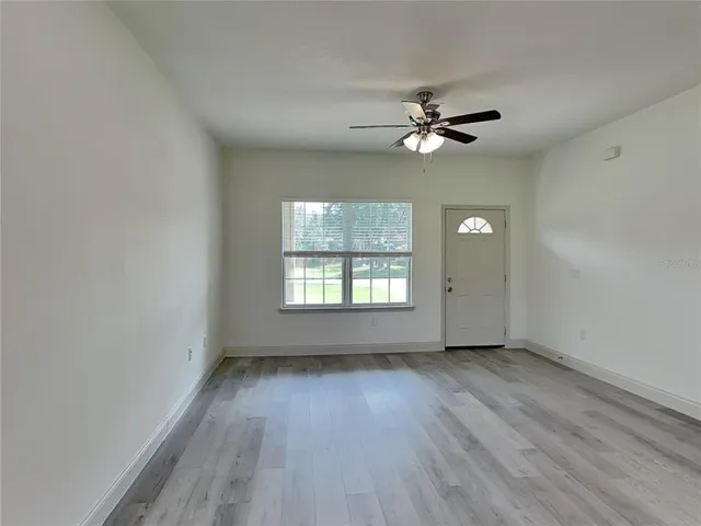 an empty room with wooden floor a ceiling fan and a window