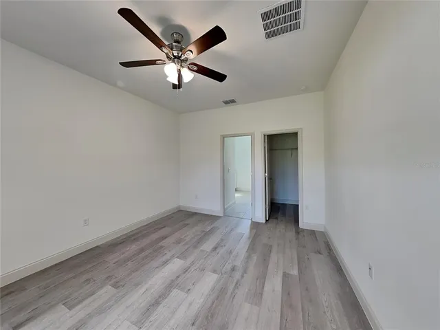 an empty room with wooden floor and a ceiling fan