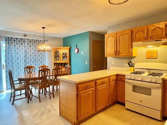 a kitchen with stainless steel appliances granite countertop a stove top oven a sink dishwasher and white cabinets with wooden floor