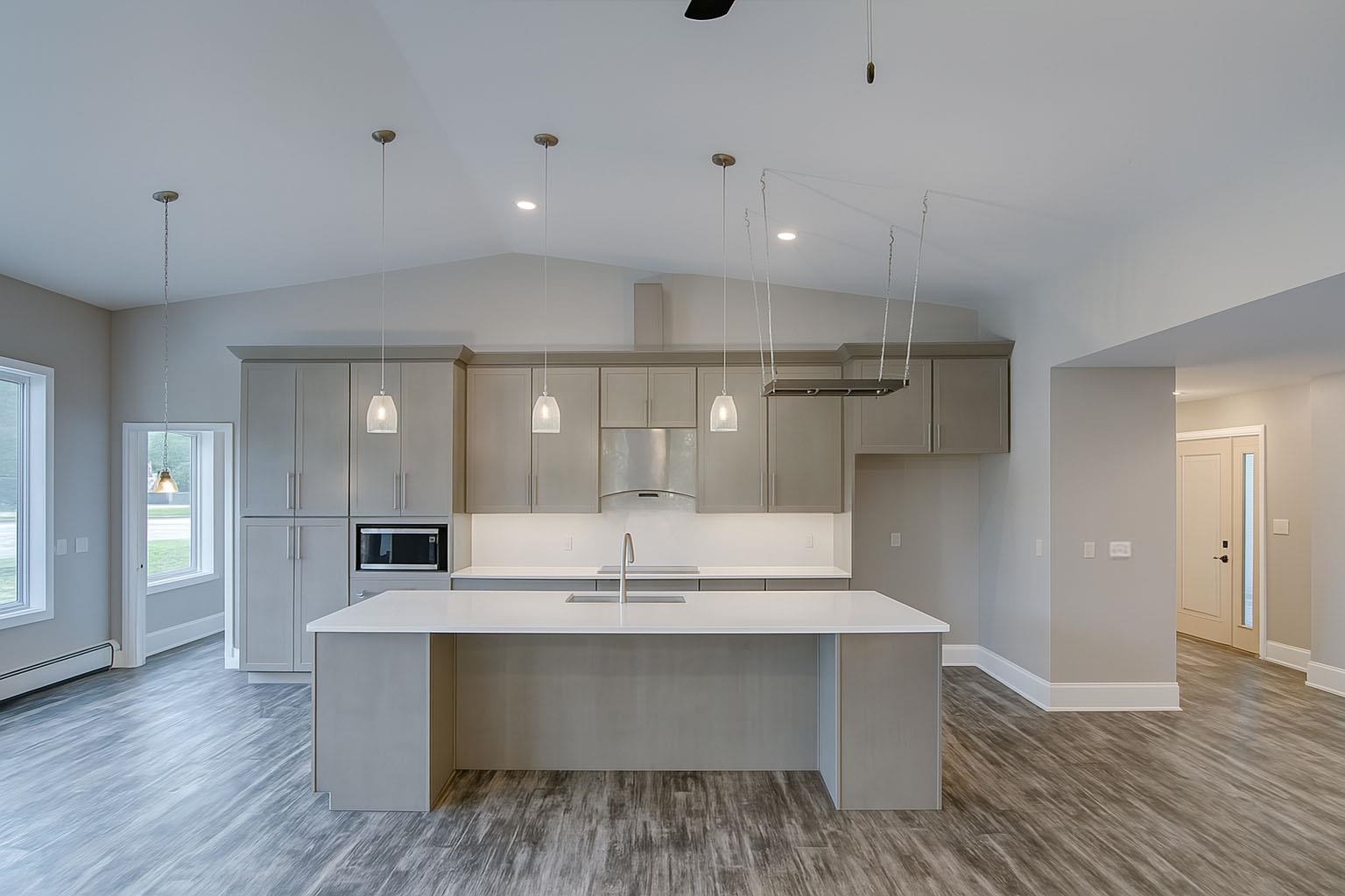 6030 Mitchell Road Iron River, WI 54847 - Photo 13 of 45 Kitchen with lofted ceiling, dark wood-style flooring, a kitchen island with sink, decorative light fixtures, and under cabinet range hood