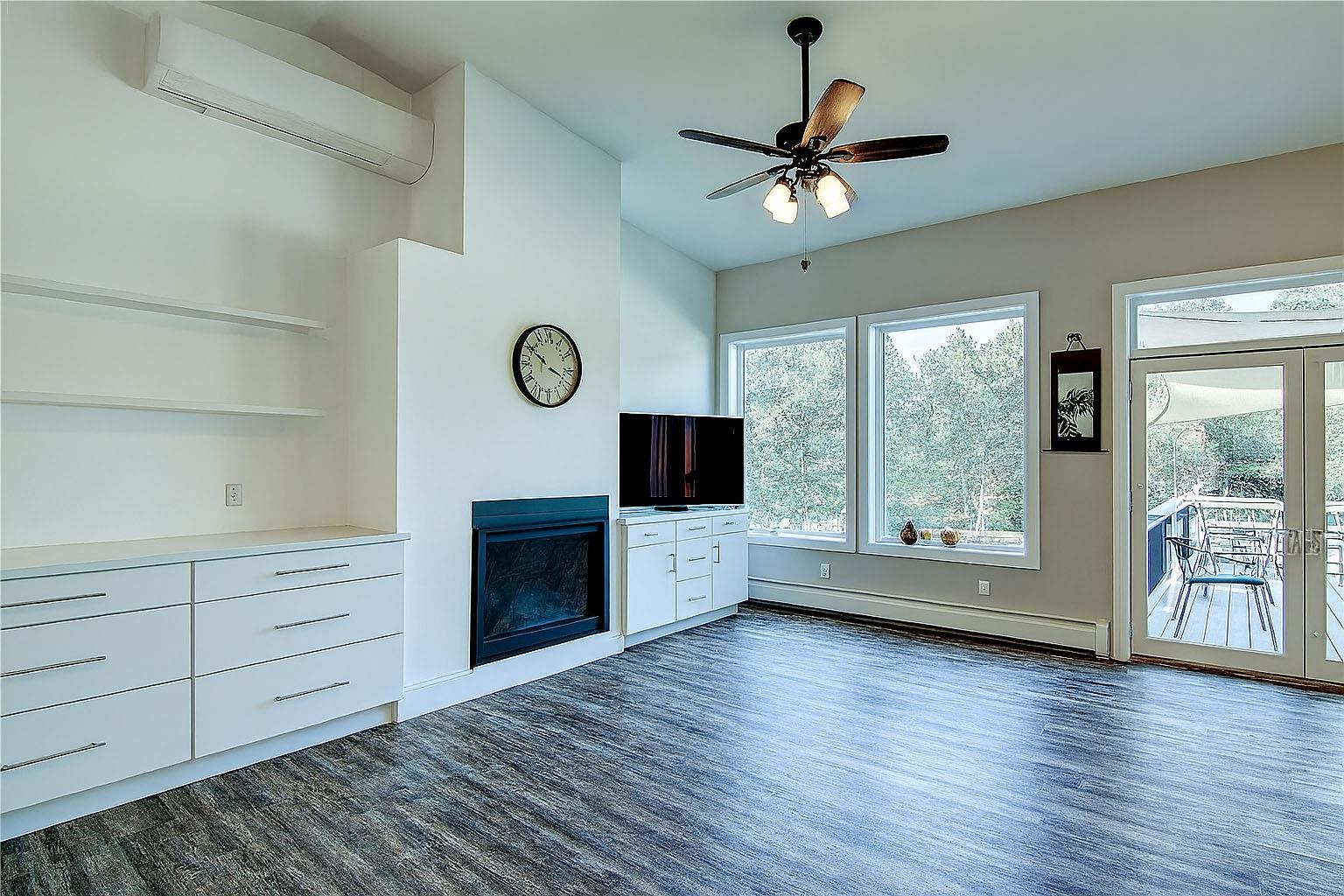 6030 Mitchell Road Iron River, WI 54847 - Photo 14 of 45 Unfurnished living room with a fireplace, dark wood finished floors, a wall unit AC, baseboard heating, and ceiling fan