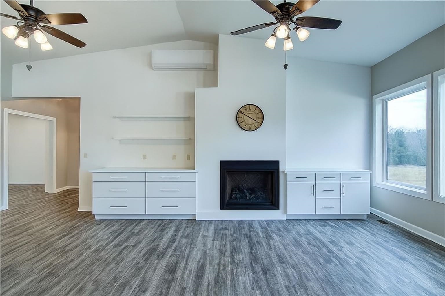 6030 Mitchell Road Iron River, WI 54847 - Photo 15 of 45 Unfurnished living room featuring a ceiling fan, dark wood-style floors, a fireplace, a wall unit AC, and lofted ceiling