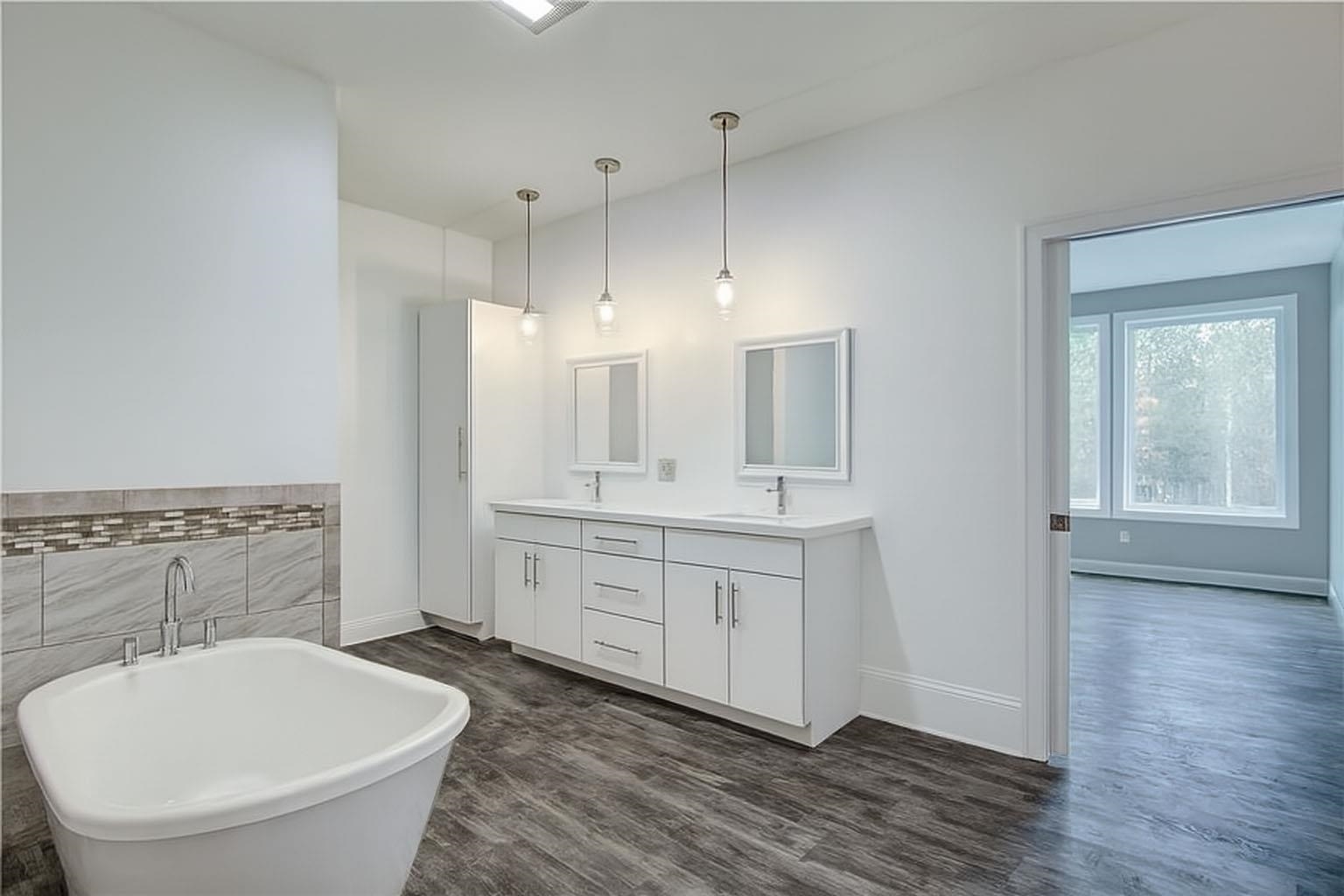 6030 Mitchell Road Iron River, WI 54847 - Photo 18 of 45 Full bath featuring double vanity, a freestanding tub, dark wood finished floors, and tile walls