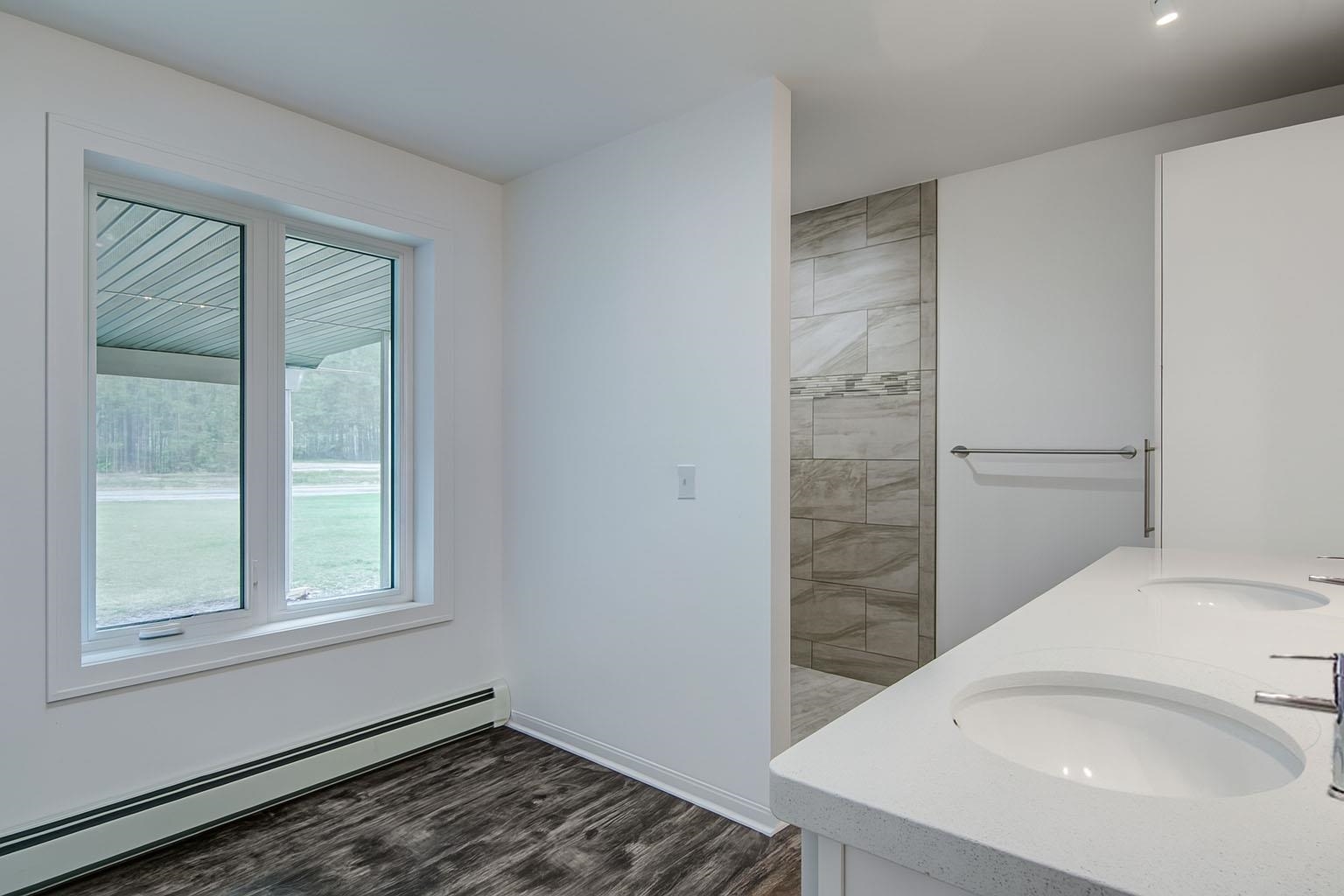 6030 Mitchell Road Iron River, WI 54847 - Photo 19 of 45 Bathroom with a baseboard radiator, dark wood finished floors, double vanity, and a walk in shower