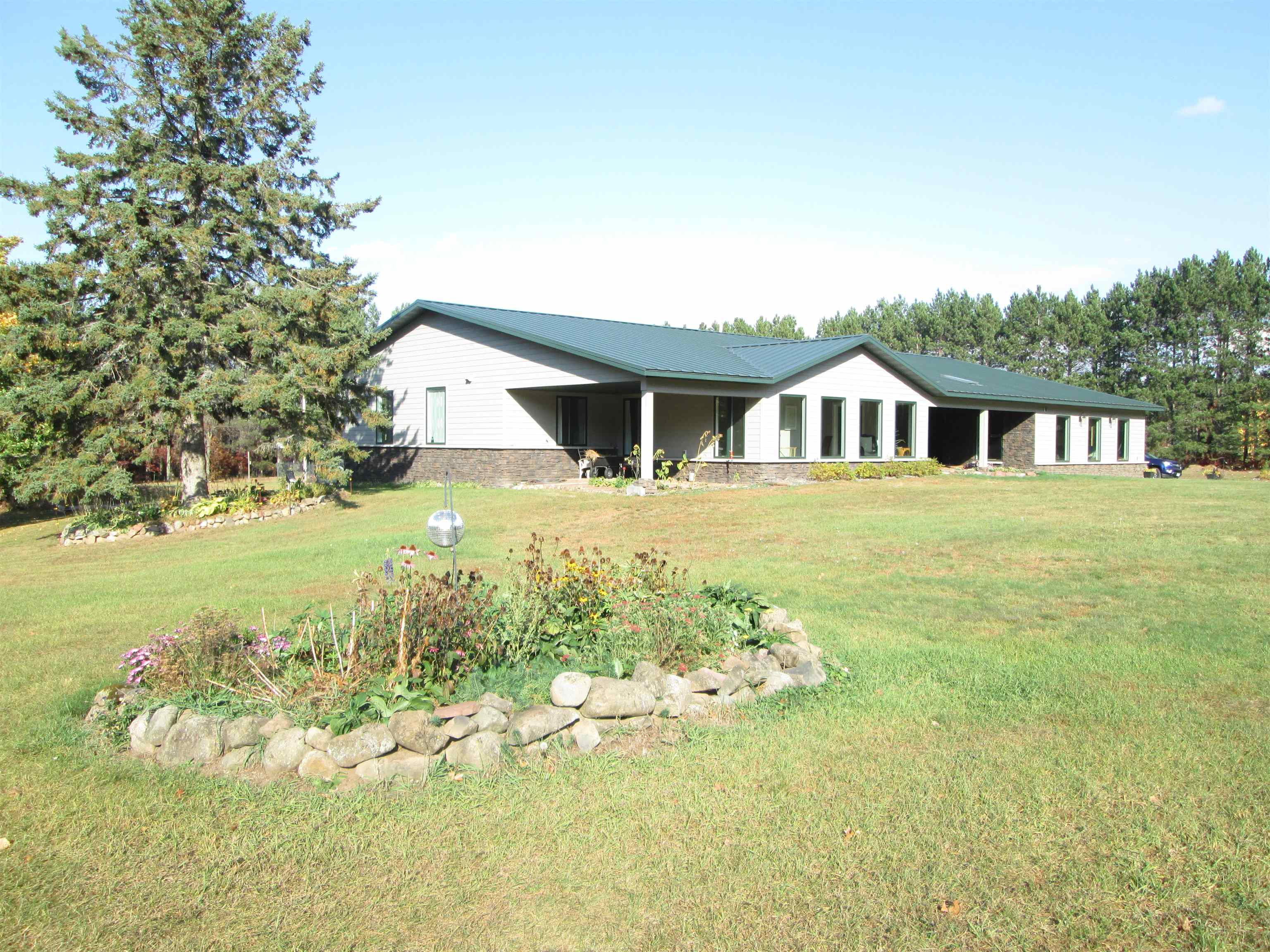 6030 Mitchell Road Iron River, WI 54847 - Photo 2 of 45 Rear view of property with a lawn, a patio area, and a metal roof