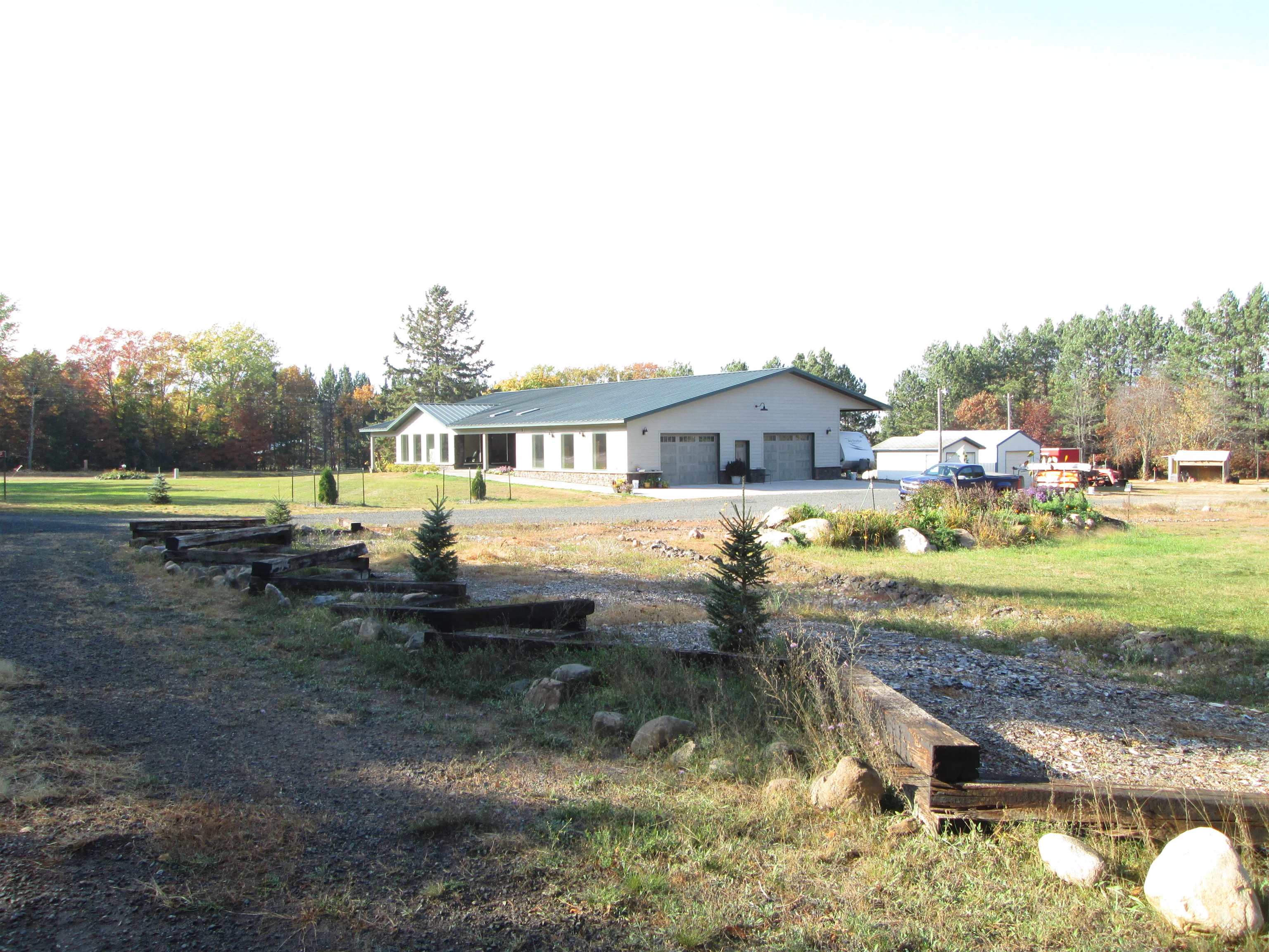 6030 Mitchell Road Iron River, WI 54847 - Photo 33 of 45 View of grassy yard with a garage, view of scattered trees, driveway, and a patio area