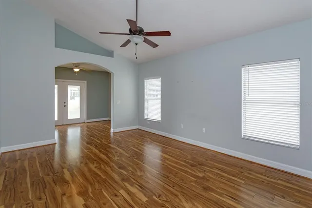 a view of an empty room with wooden floor and a window
