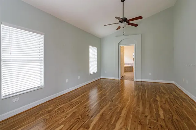 a view of empty room with wooden floor and fan