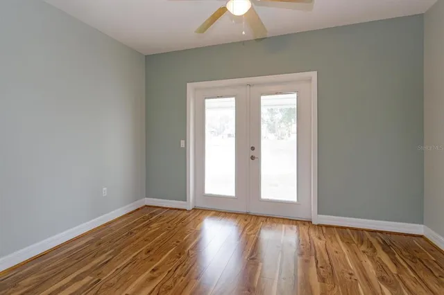 an empty room with wooden floor and windows
