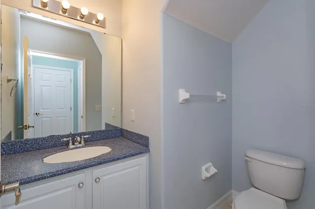 a bathroom with a granite countertop sink a toilet and a mirror