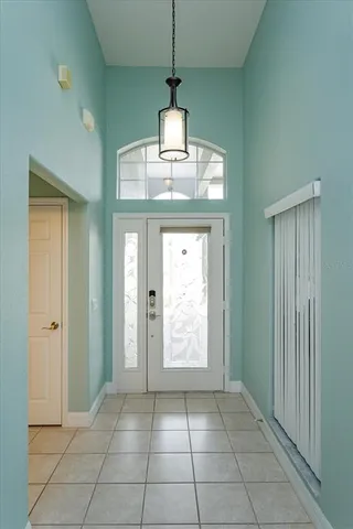 a view of an empty room with window and chandelier