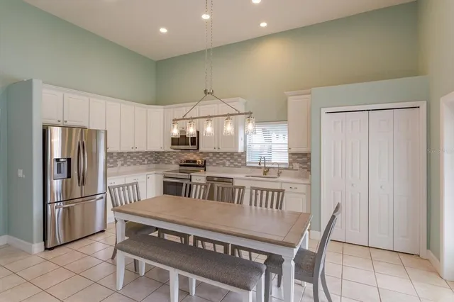 a kitchen with stainless steel appliances granite countertop a refrigerator a stove a sink a table and chairs