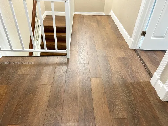 a view of a hallway with wooden floor and staircase