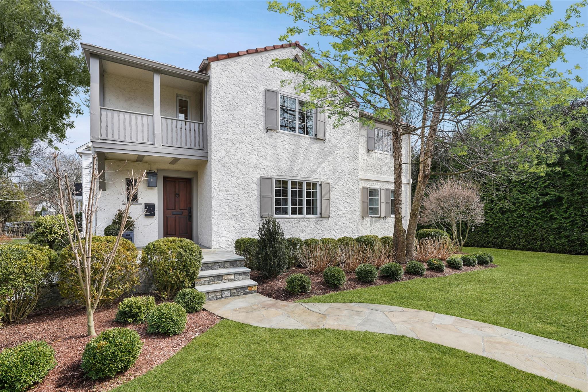 View of front of property featuring stucco siding, a front yard, and a balcony