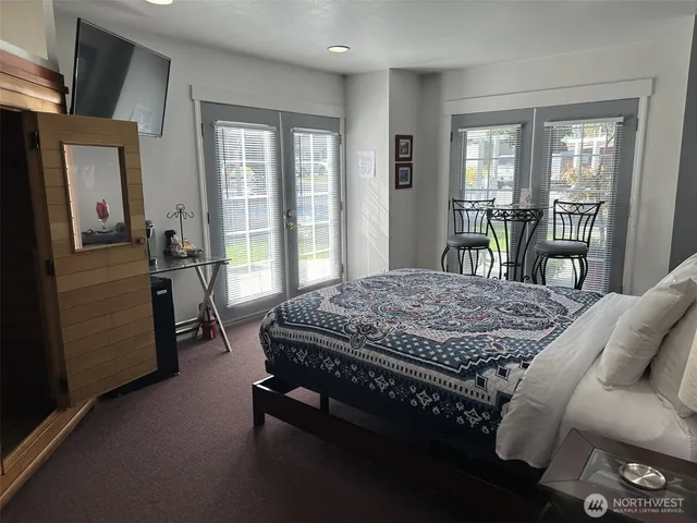 a bedroom with a bed a table and flat screen tv