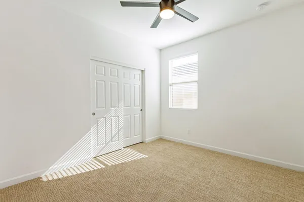 an empty room with a window and ceiling fan
