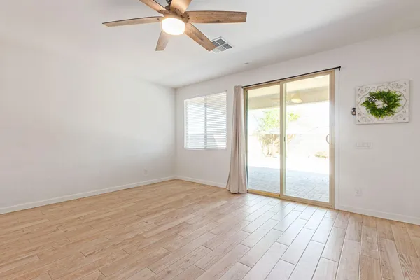 an empty room with wooden floor fan and windows