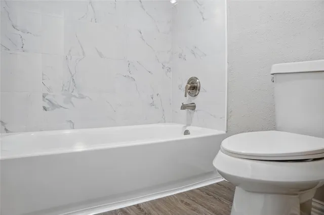 a bathroom with a white toilet and bathtub