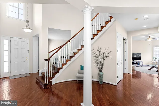 a view of a hallway with couches and a dining table with wooden floor