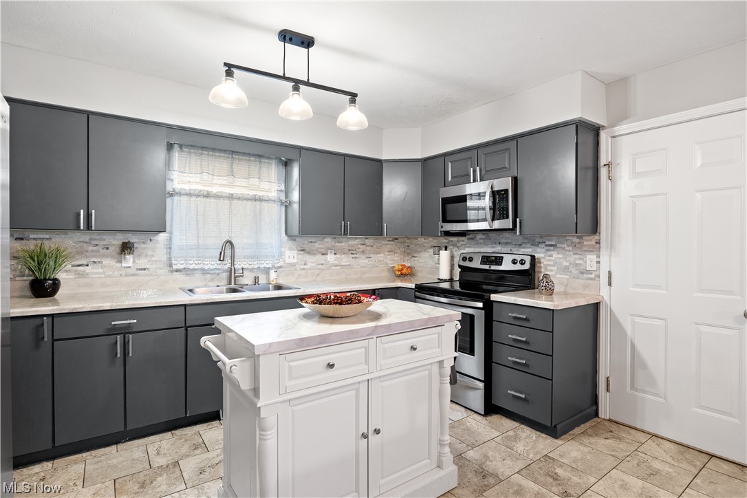 1110 Spring Road Cleveland, OH 44109 - Photo 10 of 33 Kitchen with sink, hanging light fixtures, tasteful backsplash, light tile flooring, and appliances with stainless steel finishes