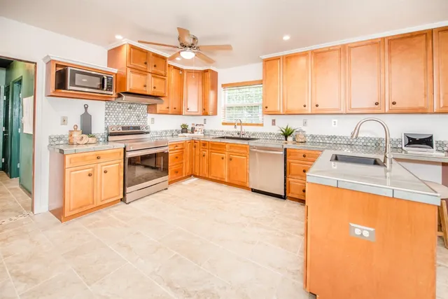 a large kitchen with stainless steel appliances granite countertop a sink and cabinets