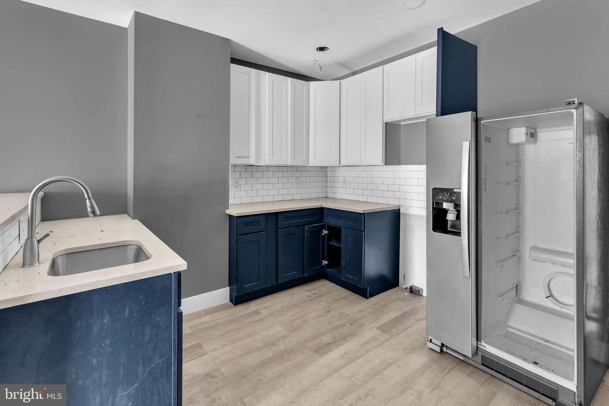 2315 East Madison Street Baltimore, MD 21205 - Photo 7 of 18 a kitchen with stainless steel appliances granite countertop a refrigerator a sink and white cabinets