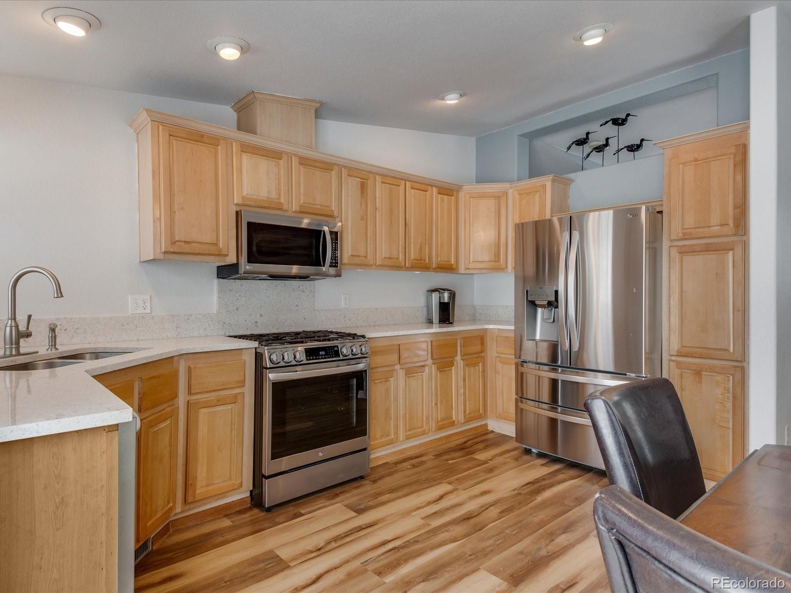 7775 Sage Green Frederick, CO 80530 - Photo 8 of 40 a kitchen with granite countertop a refrigerator stove and microwave