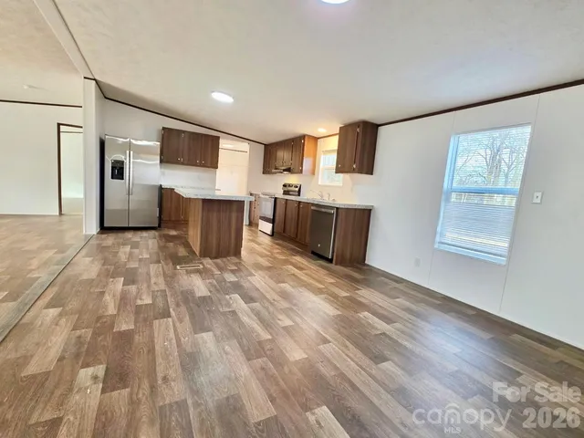 a view of a kitchen with kitchen island wooden floor and electronic appliances