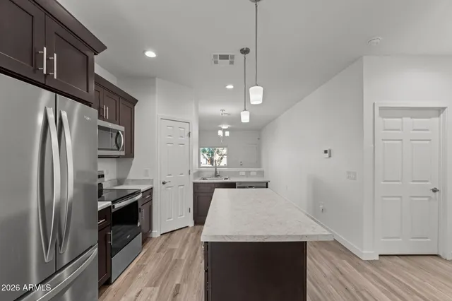 a kitchen with stainless steel appliances a sink a stove a refrigerator a center island and cabinets