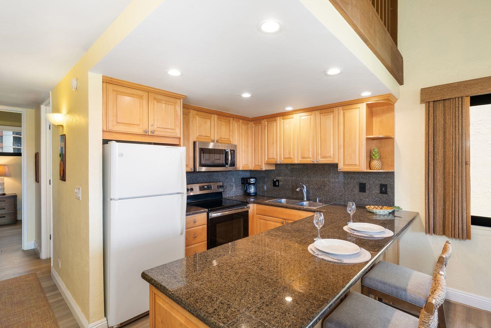 3543 Lower Honoapiilani Road, Unit J401 Lahaina, HI 96761 - Photo 7 of 25 a kitchen with stainless steel appliances granite countertop a refrigerator a stove top oven a sink dishwasher and white cabinets with wooden floor