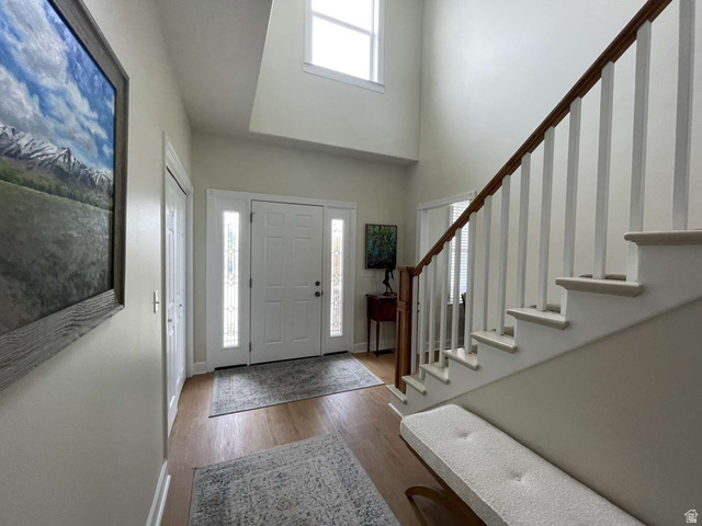 7030 West 2100 North Mendon, UT 84325 - Photo 20 of 67 Two-story foyer featuring a prominent staircase with wood railing, warm wood-finish flooring, and a double-door entry with decorative glass sidelights