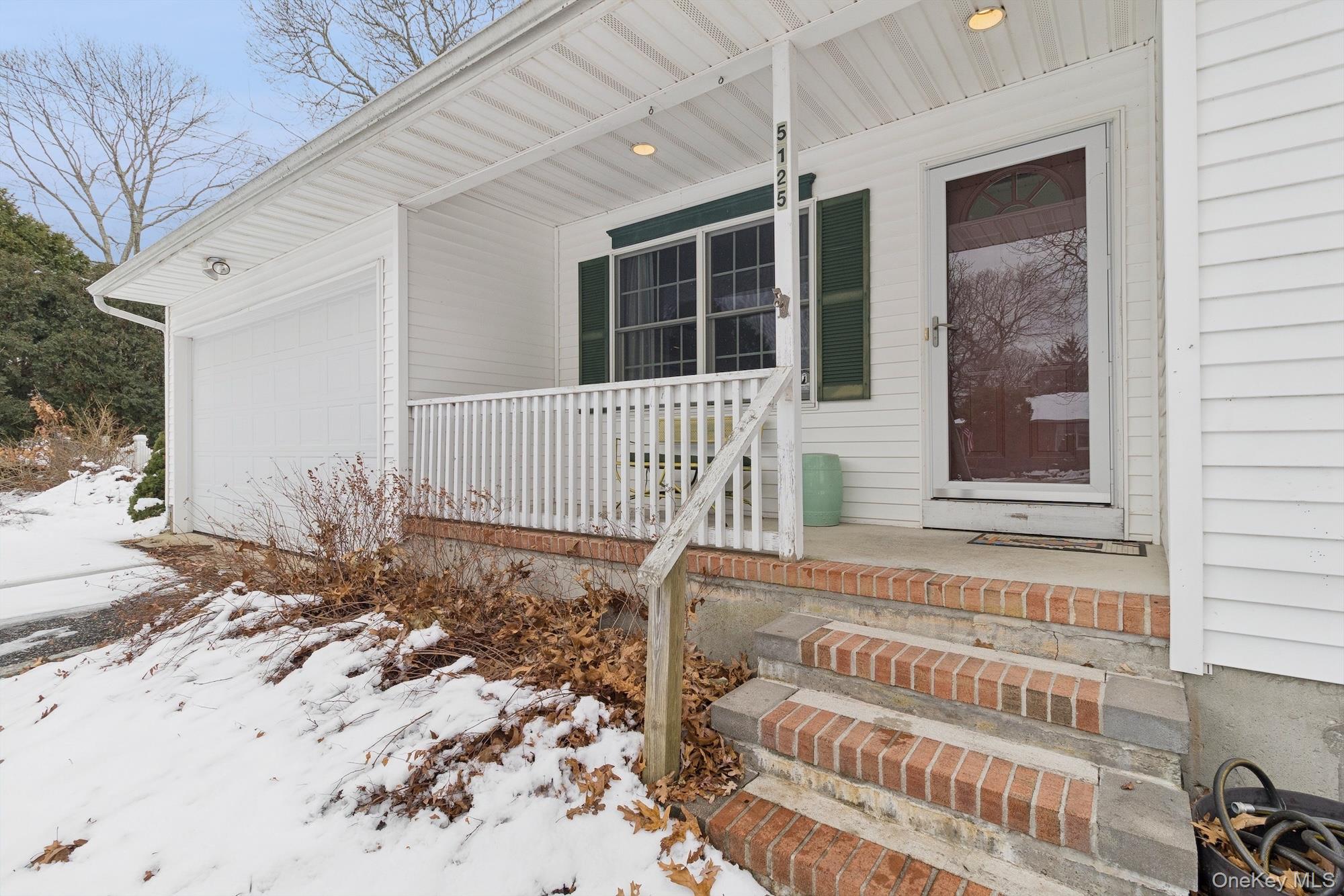 5125 Main Bayview Road Southold, NY 11971 - Photo 3 of 28 Snow covered property entrance featuring a porch and a garage