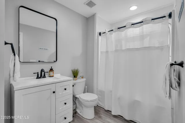 a bathroom with a toilet sink vanity and mirror