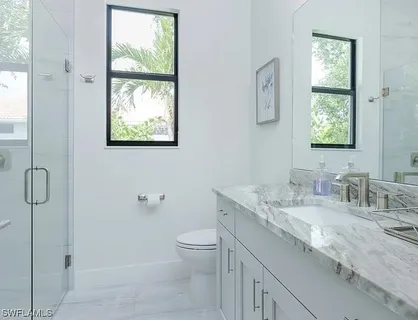 a bathroom with a granite countertop sink a toilet and a shower