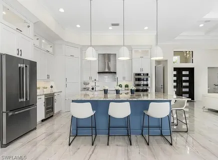 a kitchen with stainless steel appliances granite countertop a sink a stove a refrigerator cabinets and chairs