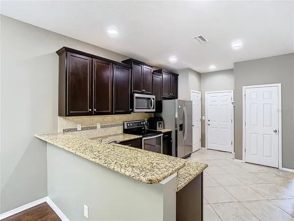 a kitchen with stainless steel appliances granite countertop a sink refrigerator and cabinets