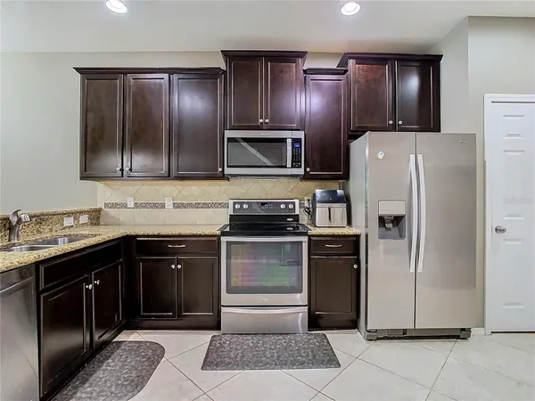 a kitchen with stainless steel appliances granite countertop a refrigerator and a stove top oven