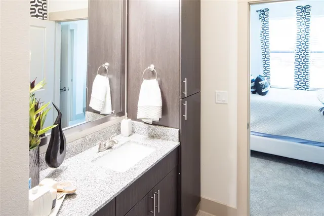 a en suite bathroom with a granite countertop sink and a mirror