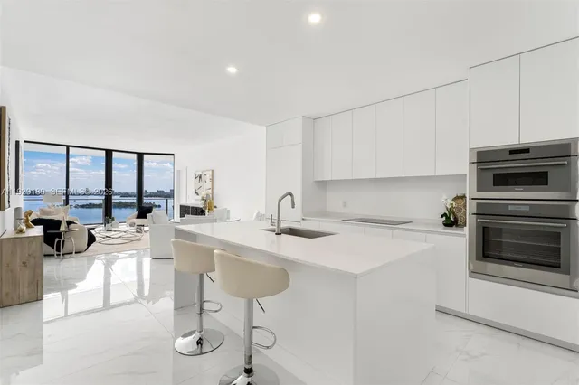 a kitchen with stainless steel appliances a stove a sink a oven a dining table and chairs